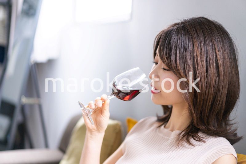 家でワインを楽しむ若い女性