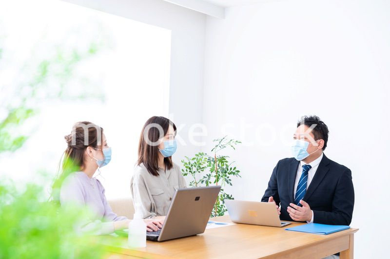マスクをしてオフィスでデスクワークをするオフィスワーカー