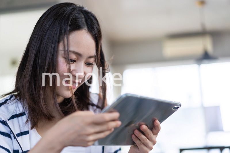 家でタブレットを使う若い女性