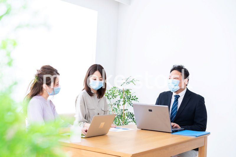 マスクをしてオフィスでデスクワークをするオフィスワーカー