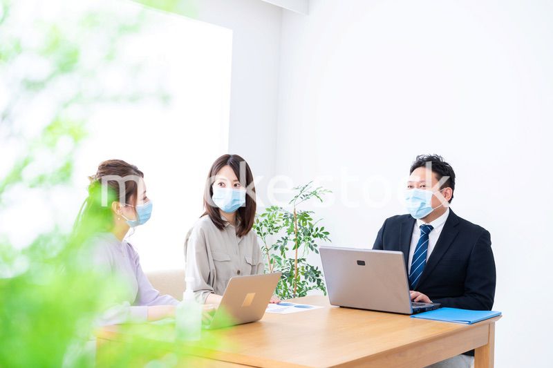 マスクをしてオフィスでデスクワークをするオフィスワーカー