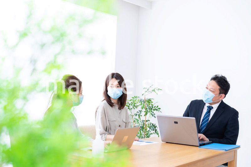 マスクをしてオフィスでデスクワークをするオフィスワーカー