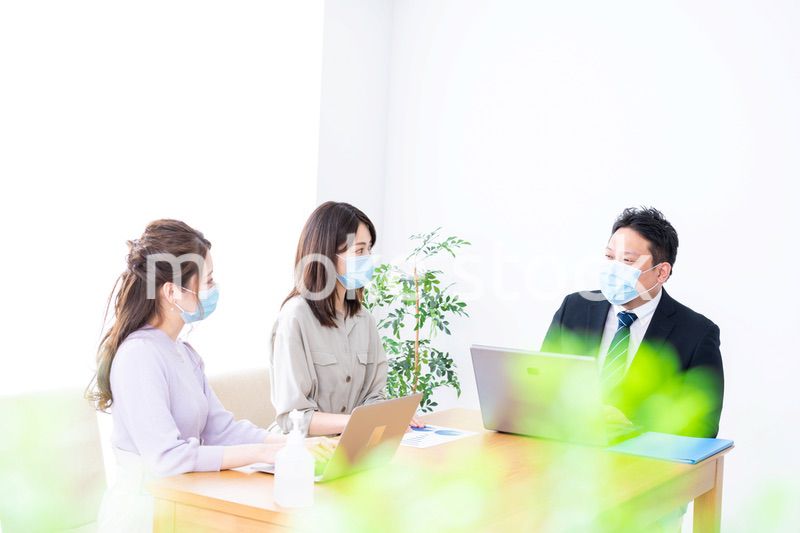 マスクをしてオフィスでデスクワークをするオフィスワーカー