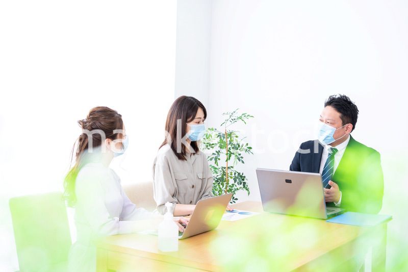 マスクをしてオフィスでデスクワークをするオフィスワーカー