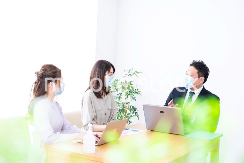 マスクをしてオフィスでデスクワークをするオフィスワーカー