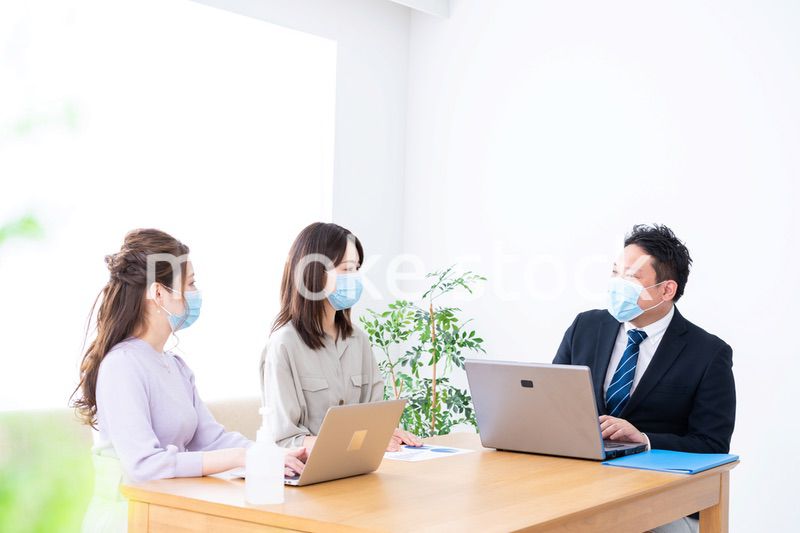 マスクをしてオフィスでデスクワークをするオフィスワーカー