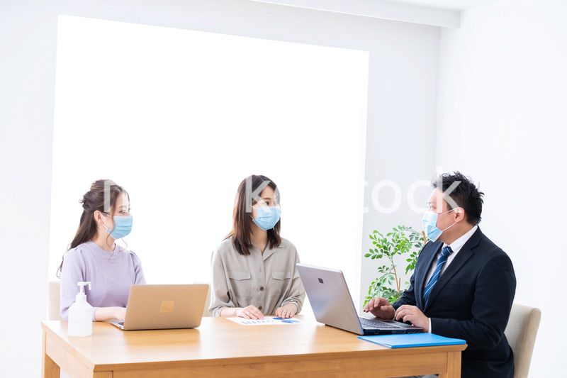 マスクをしてオフィスでデスクワークをするオフィスワーカー