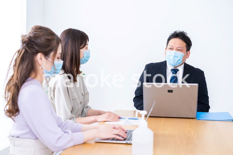 マスクをしてオフィスでデスクワークをするオフィスワーカー