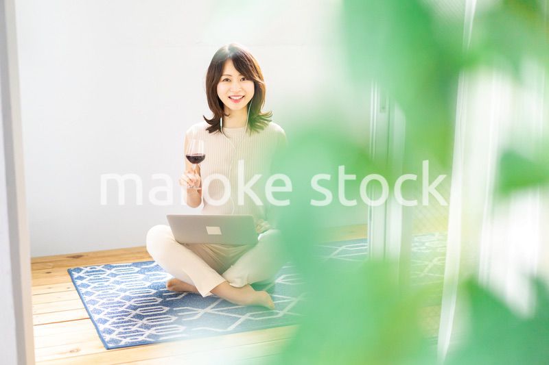 ワインを飲みながらビデオチャットをする若い女性