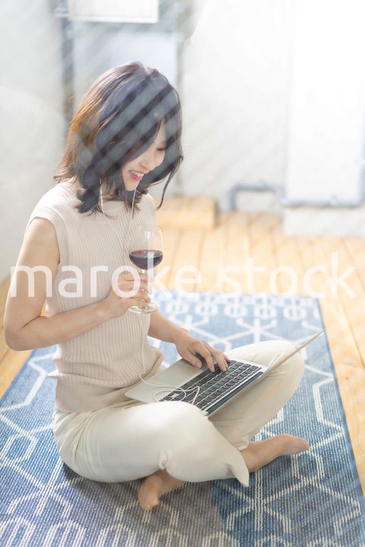 ワインを飲みながらビデオチャットをする若い女性