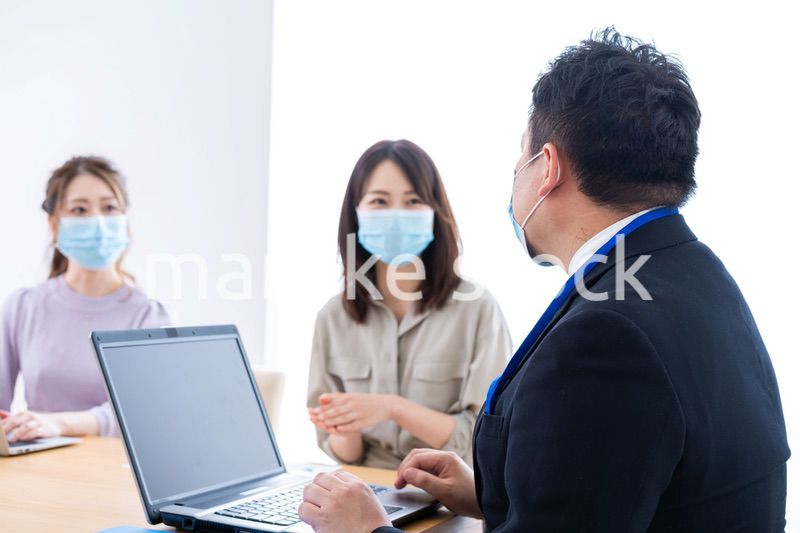 マスクをしてオフィスでデスクワークをするオフィスワーカー