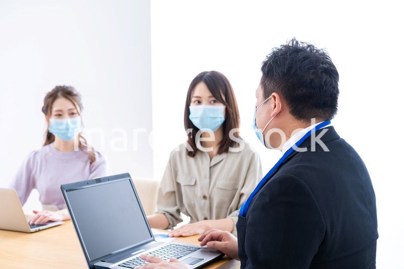 マスクをしてオフィスでデスクワークをするオフィスワーカー