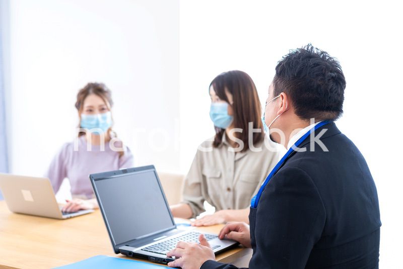 マスクをしてオフィスでデスクワークをするオフィスワーカー