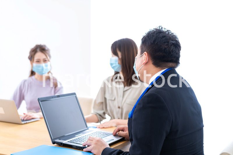 マスクをしてオフィスでデスクワークをするオフィスワーカー