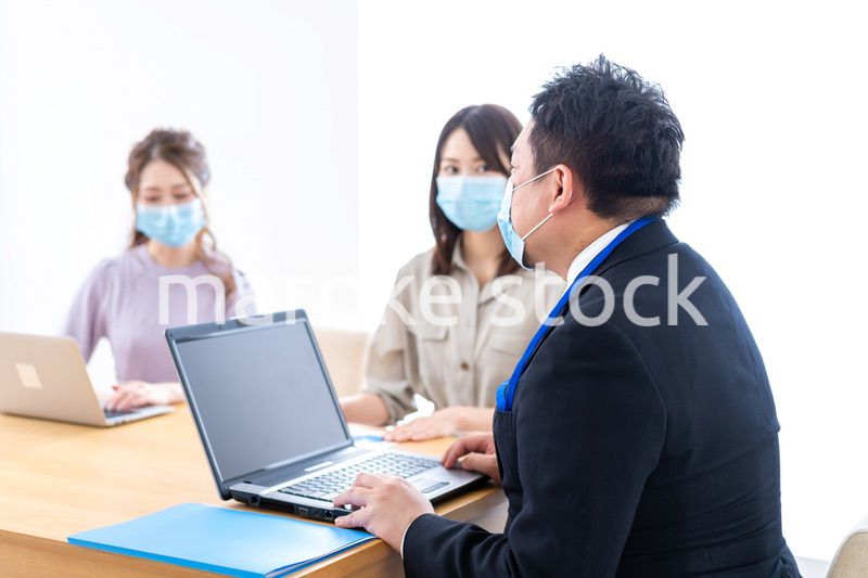 マスクをしてオフィスでデスクワークをするオフィスワーカー
