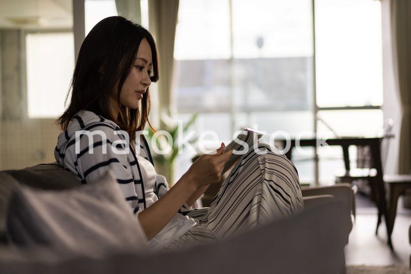 家でタブレットを使う若い女性