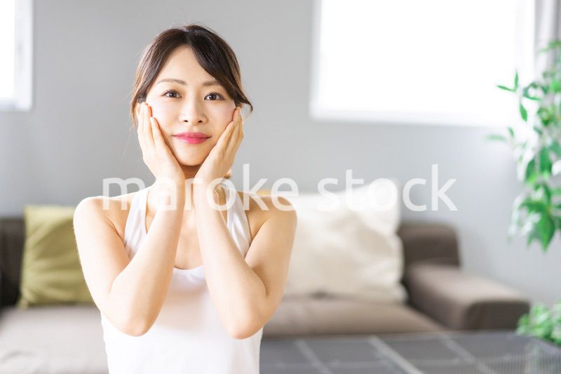 部屋でスキンケアをする若い女性