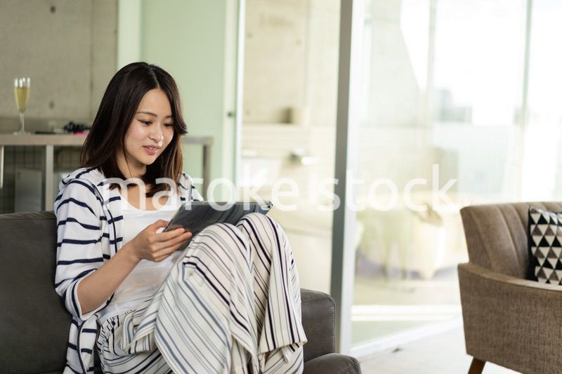 家でタブレットを使う若い女性