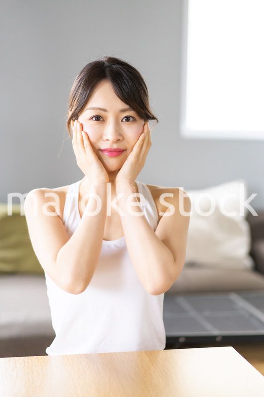 部屋でスキンケアをする若い女性