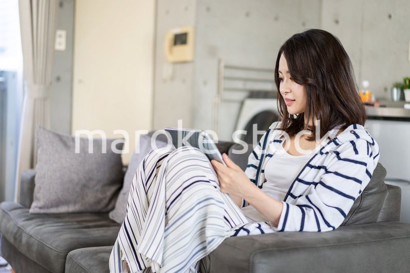 家でタブレットを使う若い女性