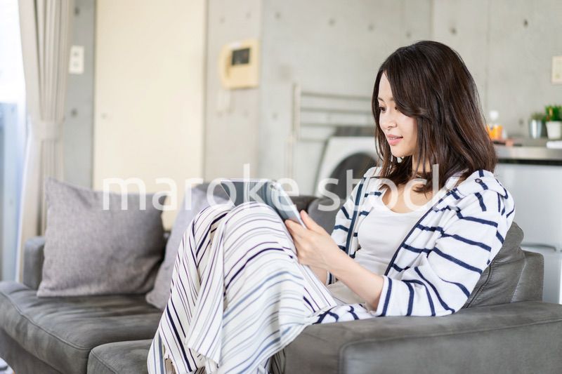 家でタブレットを使う若い女性