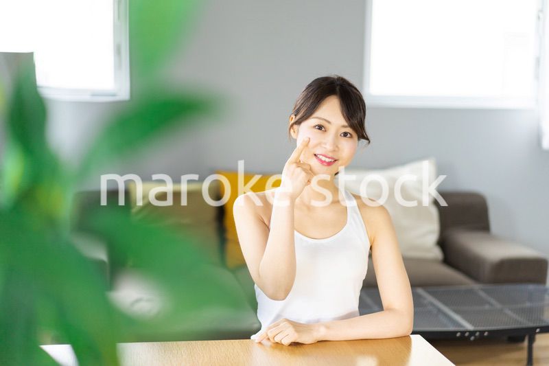 部屋でスキンケアをする若い女性