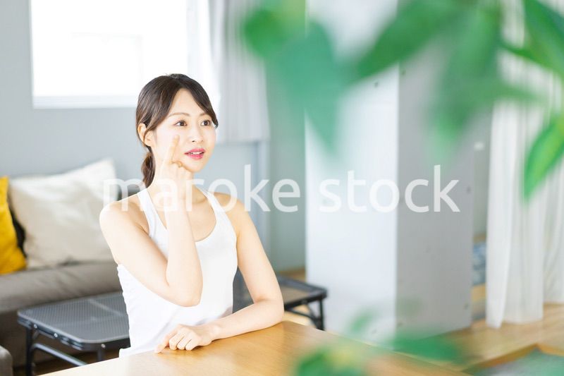 部屋でスキンケアをする若い女性