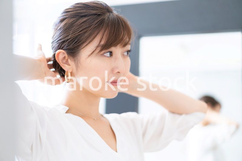 自宅でヘアスタイルを整える若い女性