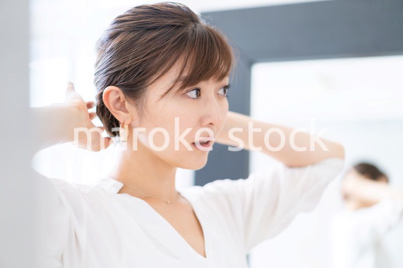自宅でヘアスタイルを整える若い女性