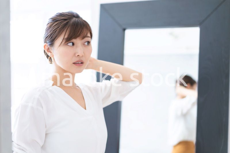 自宅でヘアスタイルを整える若い女性