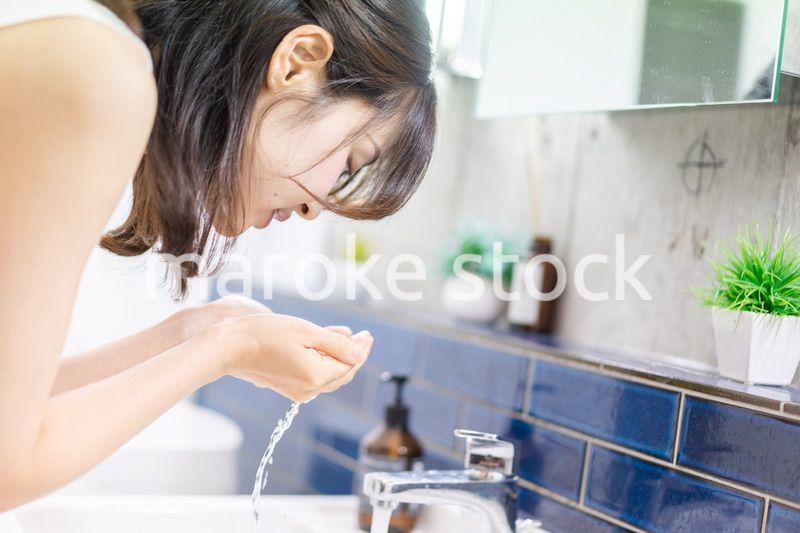 洗面所で洗顔をする若い女性