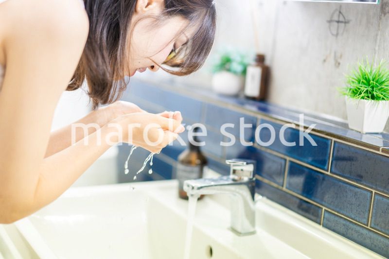 洗面所で洗顔をする若い女性
