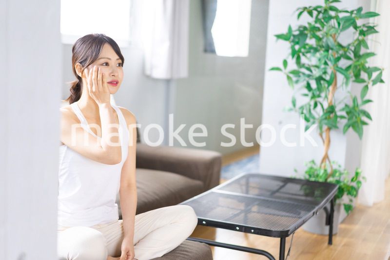 部屋でスキンケアをする若い女性