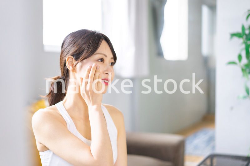 部屋でスキンケアをする若い女性