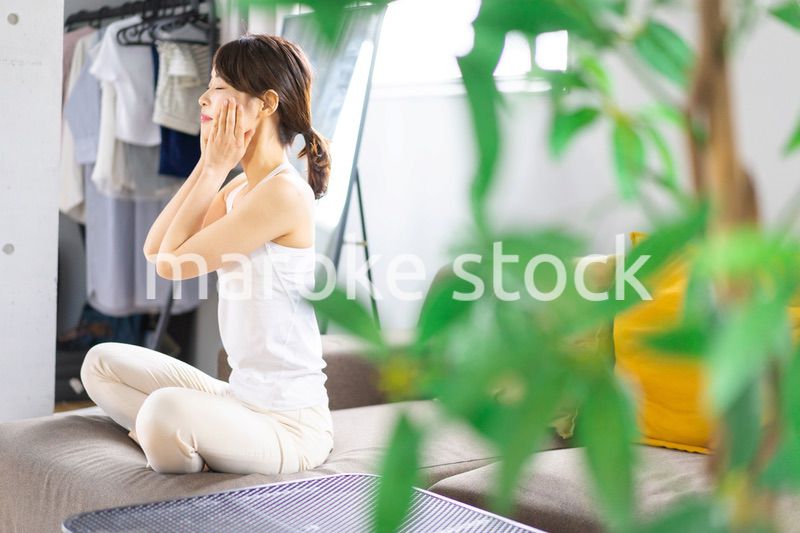 部屋でスキンケアをする若い女性