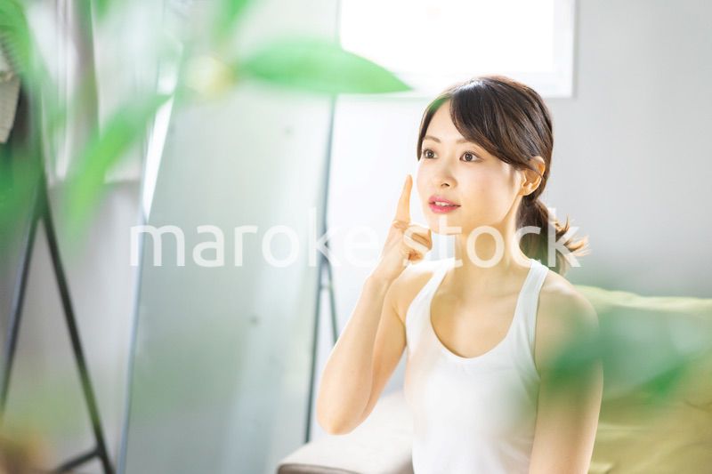 部屋でスキンケアをする若い女性