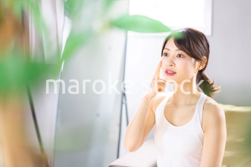 部屋でスキンケアをする若い女性