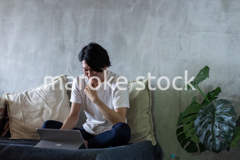 ベッドで在宅勤務をする若い男性