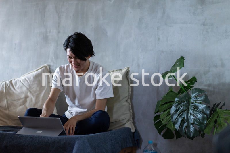 ベッドで在宅勤務をする若い男性