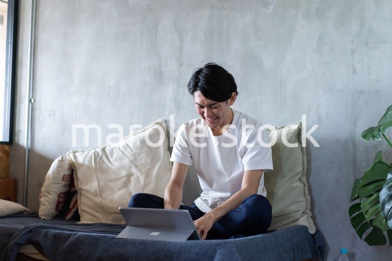 ベッドで在宅勤務をする若い男性