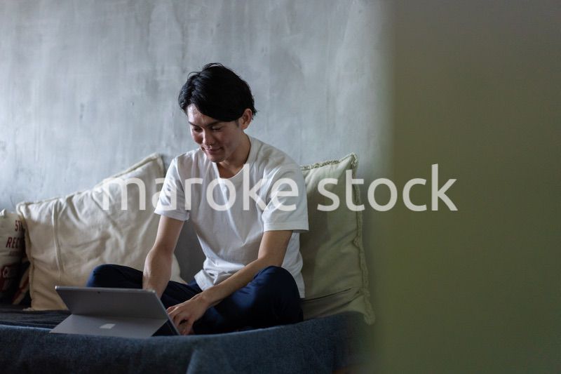 ベッドで在宅勤務をする若い男性