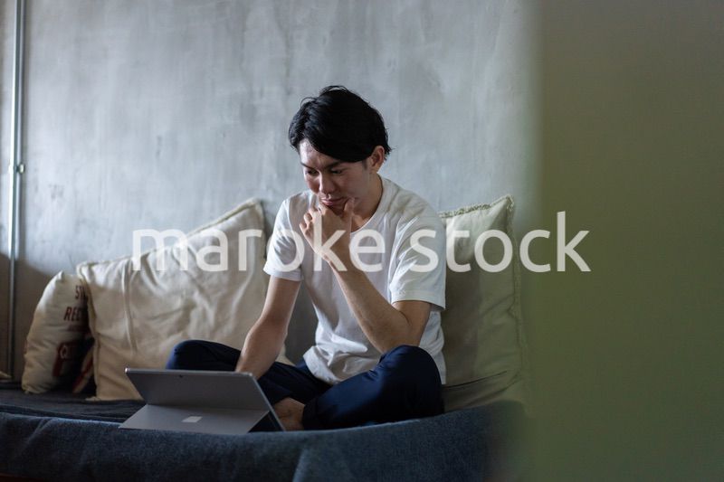 ベッドで在宅勤務をする若い男性