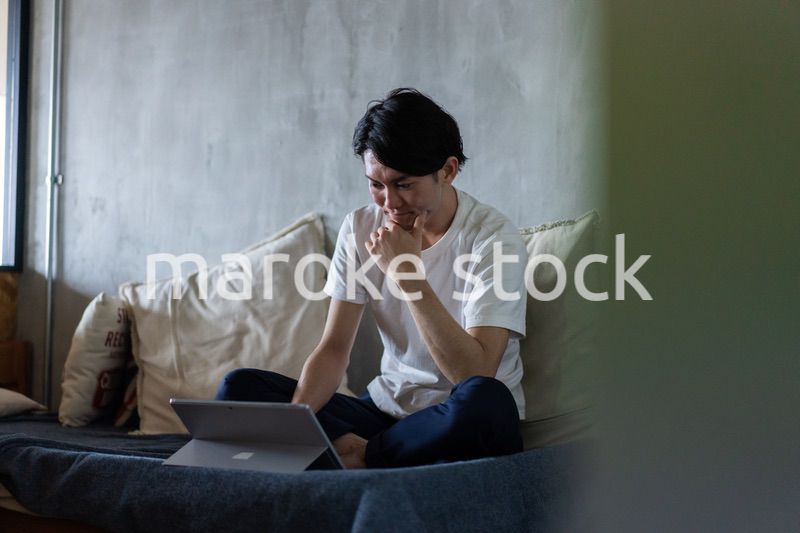 ベッドで在宅勤務をする若い男性