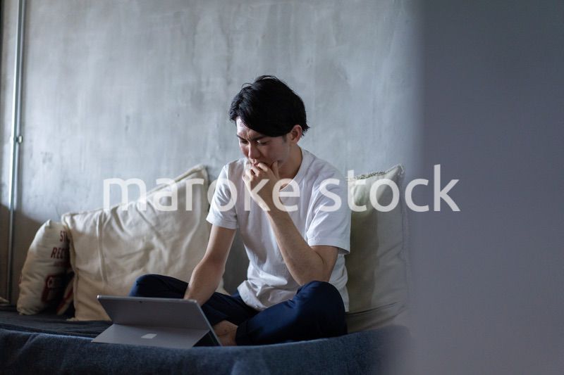 ベッドで在宅勤務をする若い男性