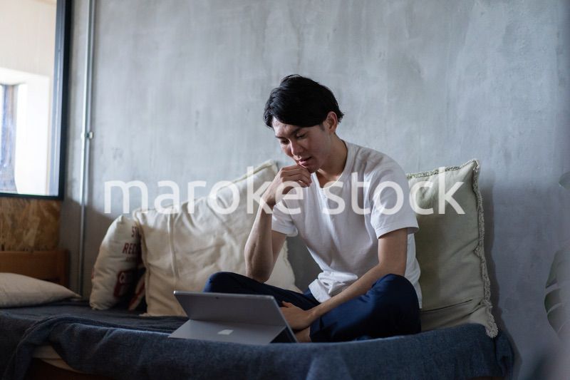 ベッドで在宅勤務をする若い男性