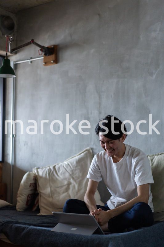 ベッドで在宅勤務をする若い男性