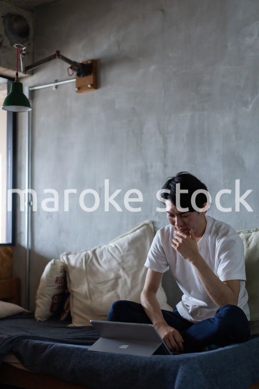 ベッドで在宅勤務をする若い男性