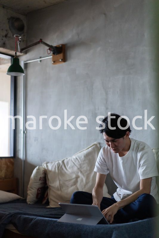 ベッドで在宅勤務をする若い男性