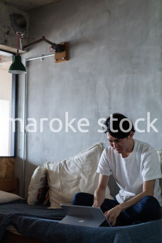 ベッドで在宅勤務をする若い男性