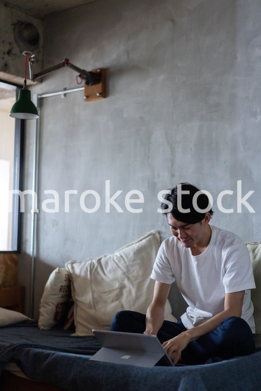 ベッドで在宅勤務をする若い男性